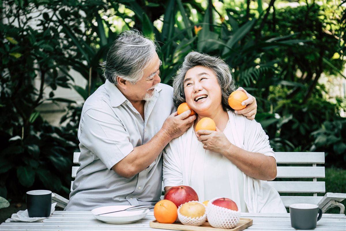 Pasangan warga emas ketawa sambil makan buah