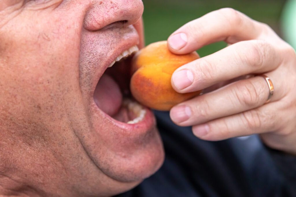 Lelaki warga emas menggigit buah dengan selesa